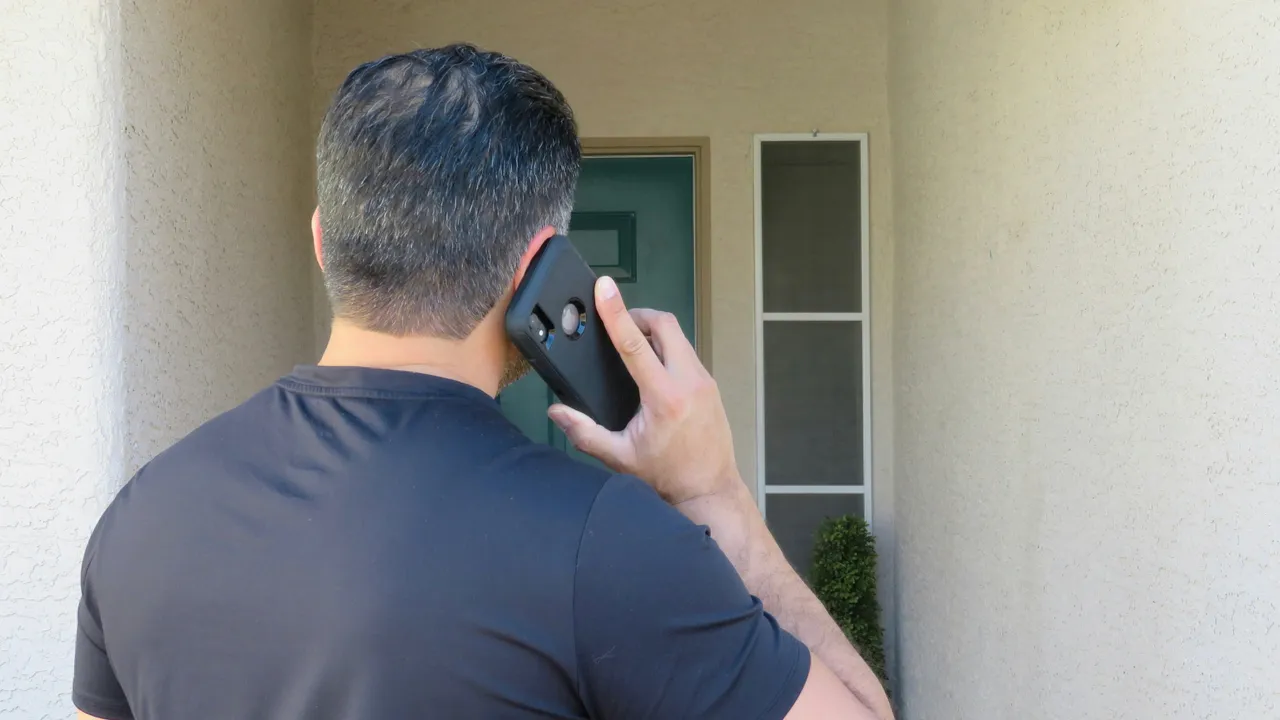 Un agent immobilier prenant un appel devant une maison.